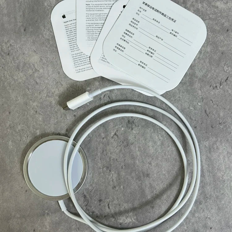 White circular wireless charging pad with coiled cable and instruction manuals displayed on gray concrete surface.
