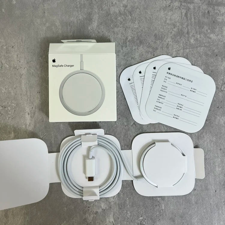 Apple MagSafe Charger unboxed on gray concrete surface, showing white circular magnetic charging pad, USB-C cable, power