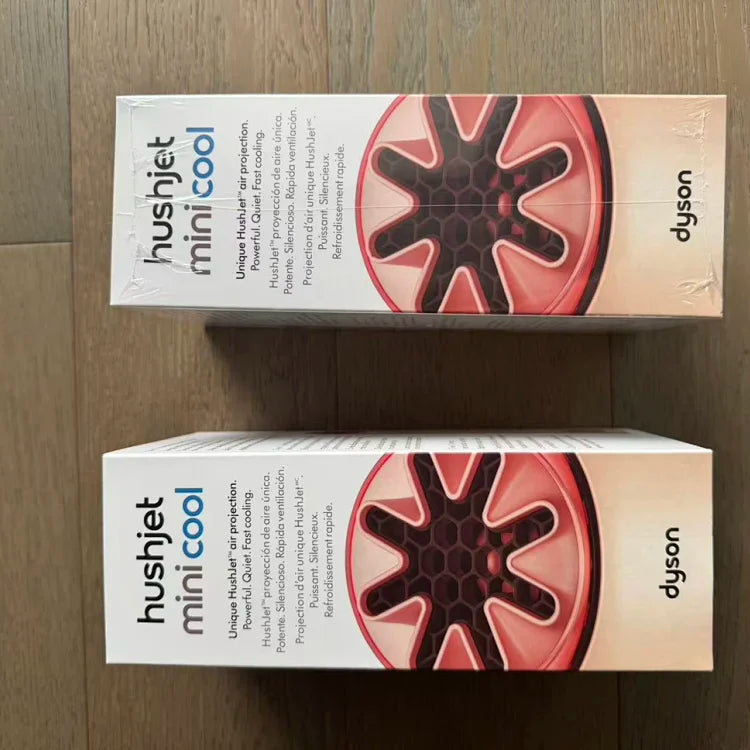 Two white cardboard boxes with Dyson branding displaying a red and black circular fan motor/blade design against a wooden