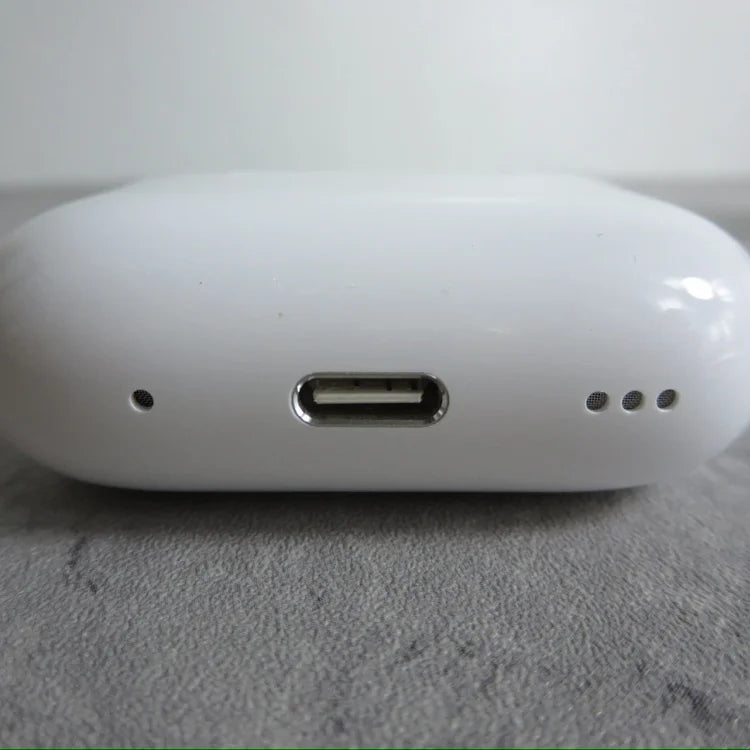 White oval-shaped device with USB-C port in center and three small circular openings on right side, photographed on gray
