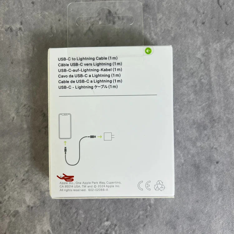White cardboard packaging box for USB-C to Lightning cable displayed flat on gray concrete surface, showing product diagram