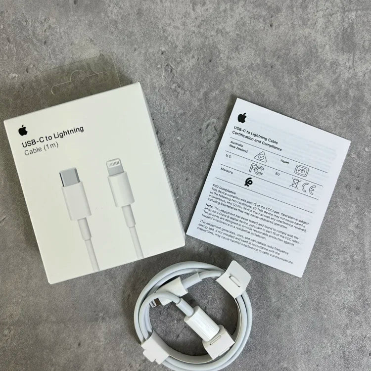 White Apple USB-C to Lightning cable with coiled connector, displayed with packaging showing product images and regulatory